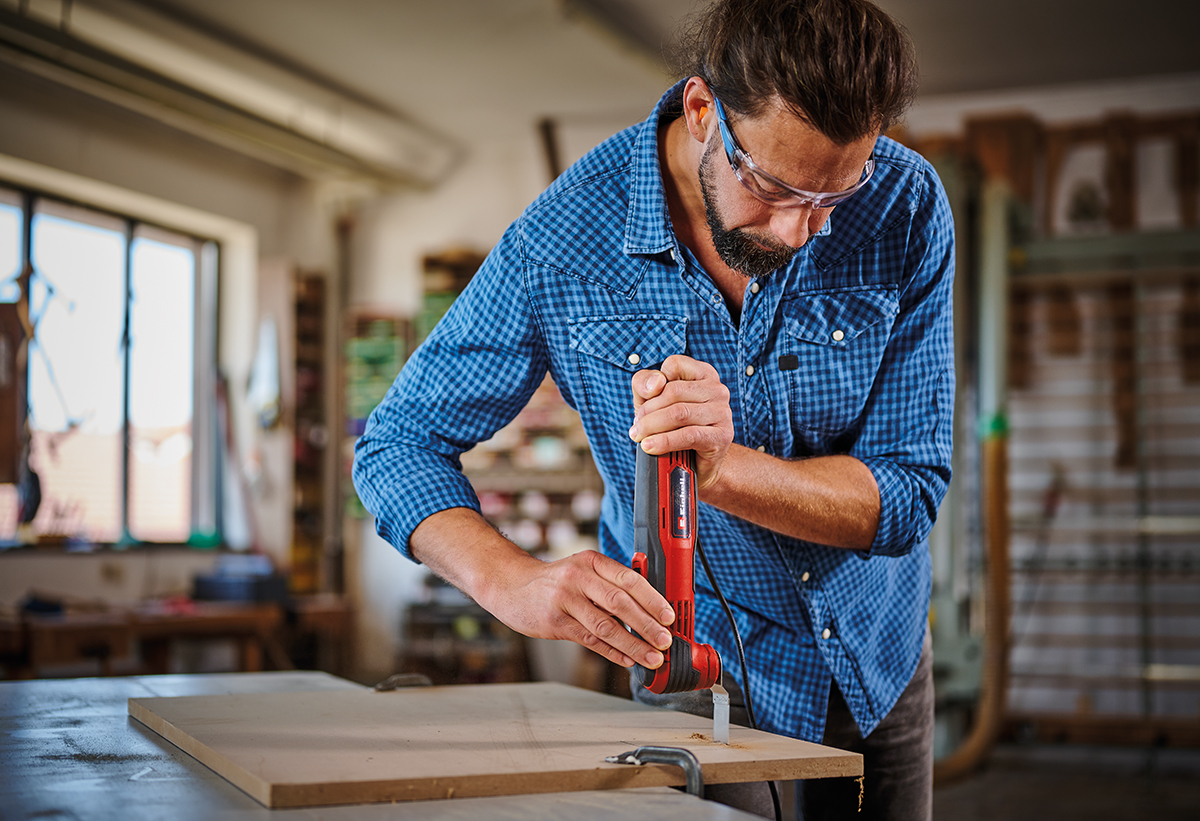 Απεικονίζεται άνδρας να χρησιμοποιεί το πολυεργαλείο σε ξύλινη επιφάνεια.